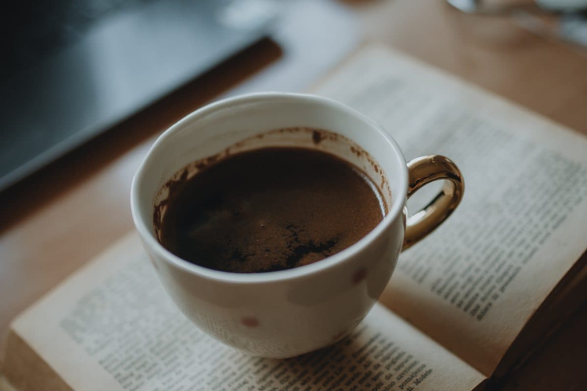 Open book and coffee on a wooden desk — choosing how to learn French: teacher, app, or self-study